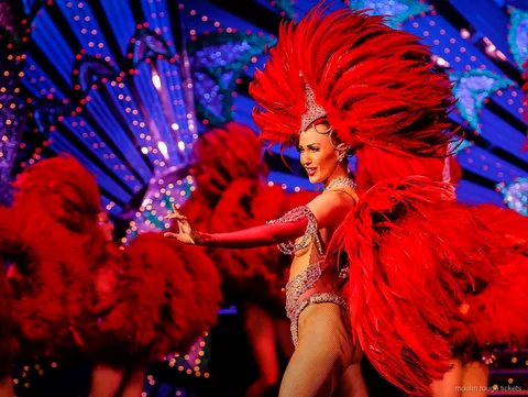 Ballerina con un grande ventaglio di piume rosse davanti a una scenografia blu, biglietti Moulin Rouge
