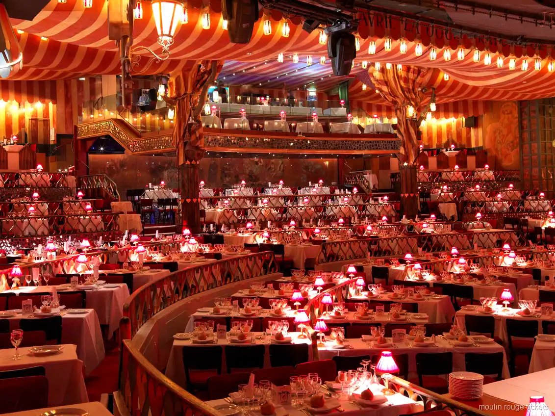 Billets Moulin Rouge : la salle du cabaret avec plafond rayé rouge, tables en gradins et lampes roses