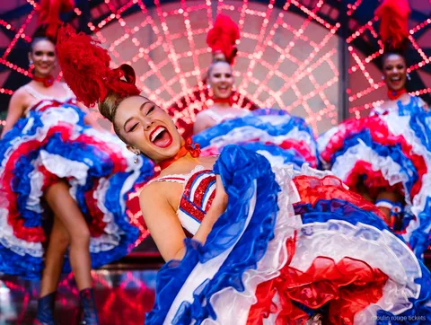 Ballerina di cancan sorridente con gonna a balze rossa, bianca e blu, biglietti cena e spettacolo Moulin Rouge