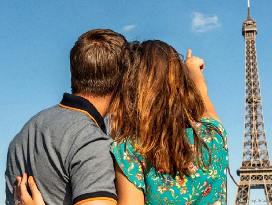 Paar von hinten zeigt bei blauem Himmel auf den Eiffelturm, Teil des Kombi-Abends mit Moulin Rouge Tickets