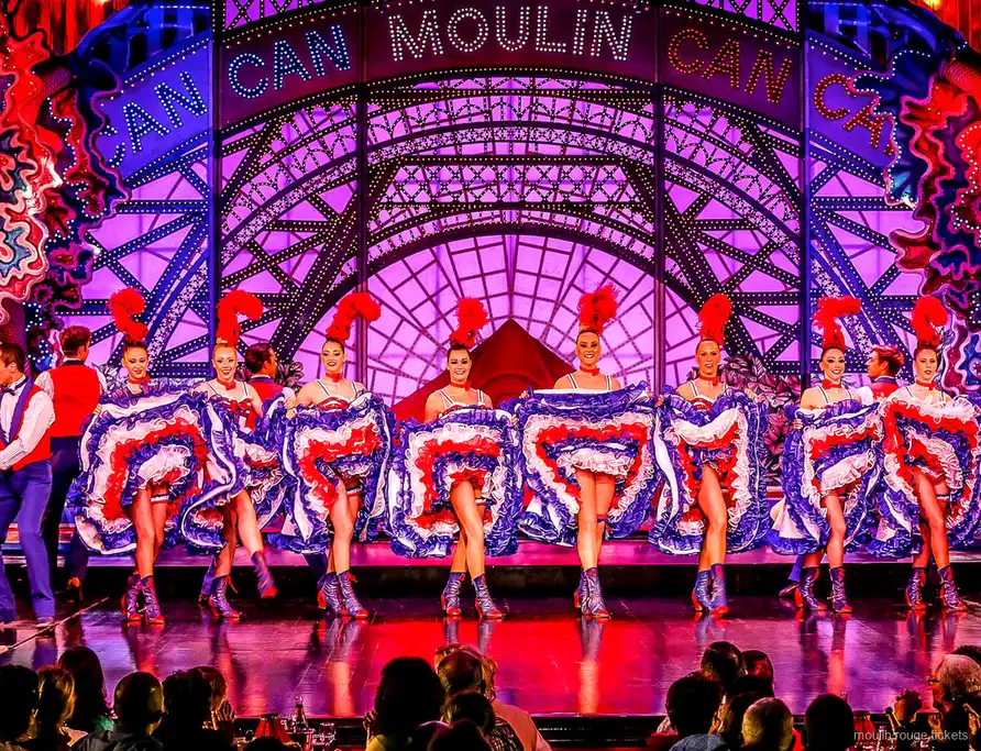 Fila de French Cancan amb faldilles tricolors sota el rètol lluminós Moulin, entrades Moulin Rouge