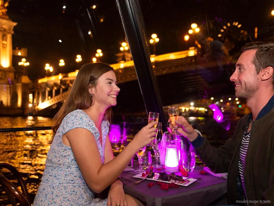 Gece Seine nehri yemekli turunda şampanya ile kadeh kaldıran çift, Moulin Rouge biletleri ile gösteri öncesi