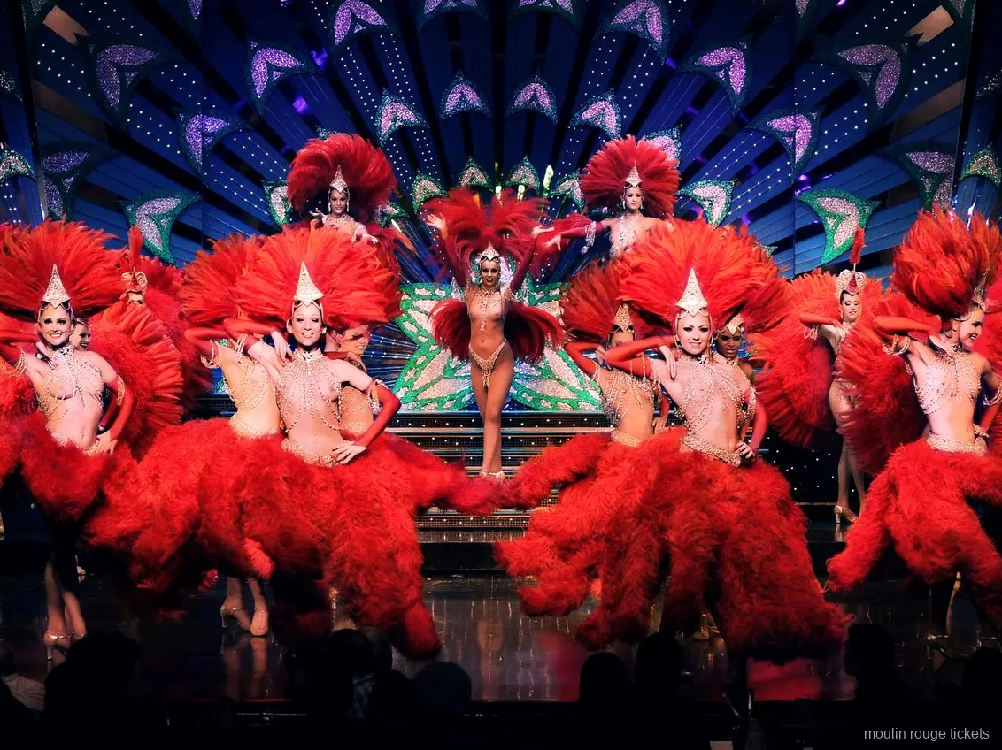 Tancerki w czerwonych piórach i lśniących nakryciach głowy na scenie, rewia, którą zobaczysz z biletami Moulin Rouge