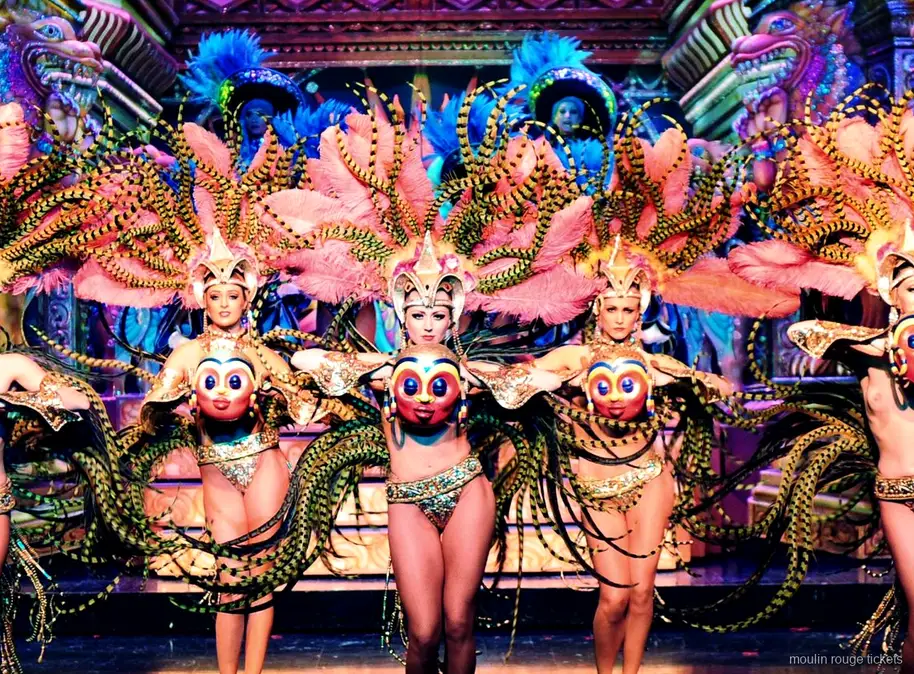Danseressen met roze gestreepte verenvleugels en gouden maskers voor een rijk decor, Moulin Rouge dinner show