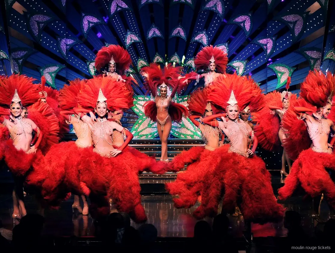 Dancers in red feather costumes and jewelled headdresses on stage, the revue you see with Moulin Rouge tickets