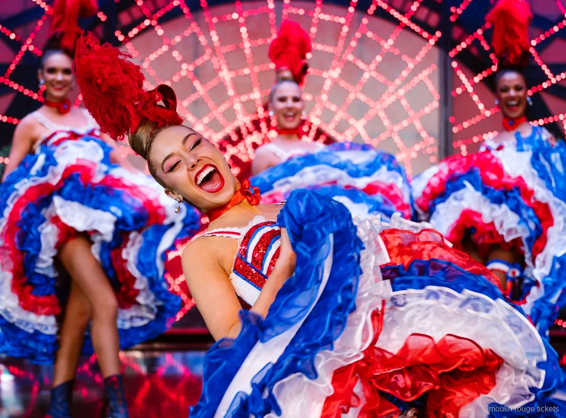 赤白青のフリルスカートを持ち上げて大きく笑うカンカンの踊り子と後ろに並ぶダンサーたち、ムーランルージュ ディナーショー チケット