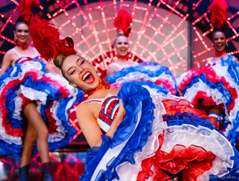 Laughing cancan dancer lifting a red, white and blue ruffled skirt, Moulin Rouge dinner show tickets