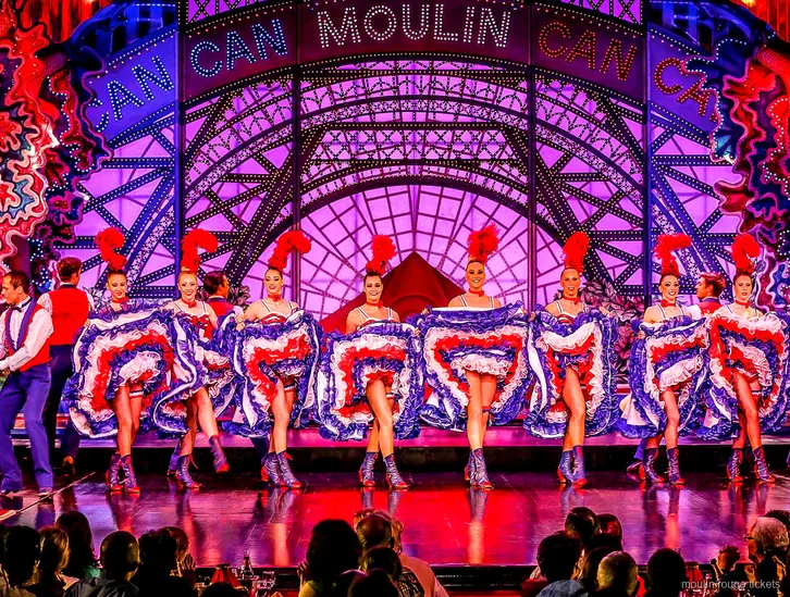 French Cancan line in tricolour skirts under the lit Moulin sign, the stage view with Moulin Rouge tickets