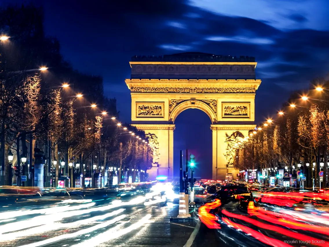 Verlichte Arc de Triomphe bij nacht aan het eind van de Champs Élysées met lichtsporen, route naar Moulin Rouge tickets