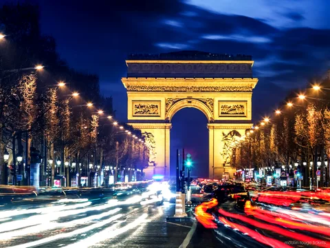 夜のシャンゼリゼ通りの先にライトアップされた凱旋門と車の光の軌跡、ムーランルージュ チケット前に巡るパリの夜景