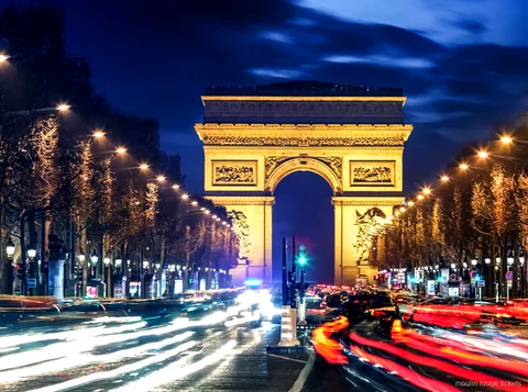 Gece Champs Élysées'nin sonunda ışıklandırılmış Zafer Takı ve araç ışık izleri, Moulin Rouge biletleri öncesi rota