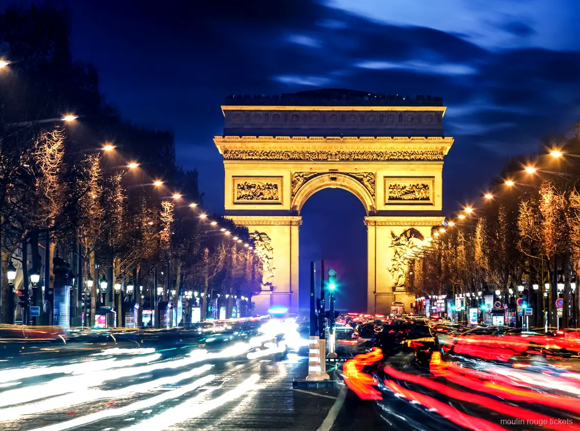 Gece Champs Élysées'nin sonunda ışıklandırılmış Zafer Takı ve araç ışık izleri, Moulin Rouge biletleri öncesi rota