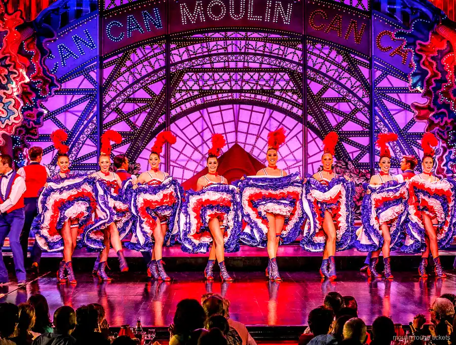 Ballarina de cancan en un salt d'espagat amb faldilla blava de volants i parella, sopar espectacle Moulin Rouge