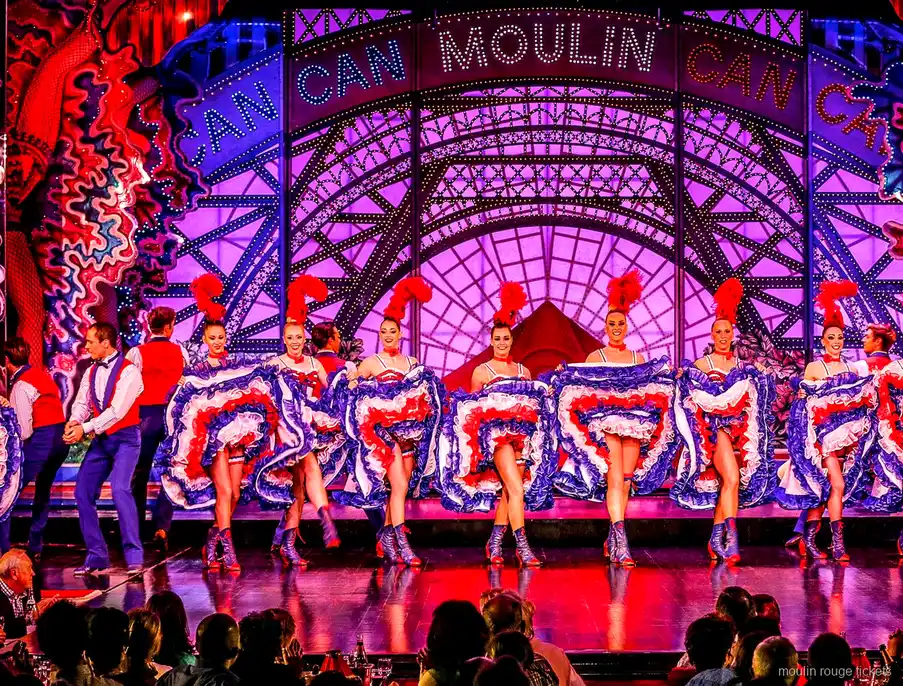 Ballarines de French cancan amb faldilles de volants davant el rètol Moulin Can Can, el xou de les entrades al Moulin Rouge
