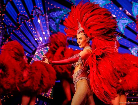 Danseuse avec un grand éventail de plumes rouges devant un décor bleu illuminé, billets Moulin Rouge