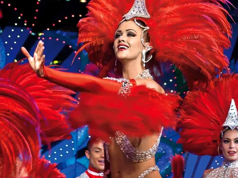 Bilety Moulin Rouge: tancerka w czerwonym pióropuszu i cekinach w świetle sceny