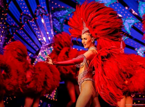 Tancerka z dużym wachlarzem z czerwonych piór przed niebieską scenografią, bilety Moulin Rouge